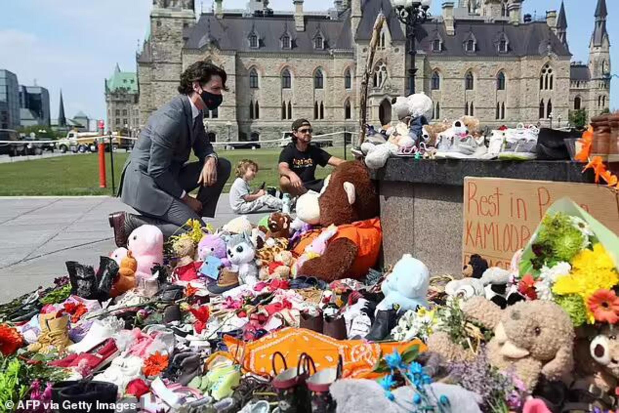 Justin Trudeau inginocchiato davanti ai fiori raccolti dopo la notizia dei 215 bambini sepolti sotto a un collegio cattolico