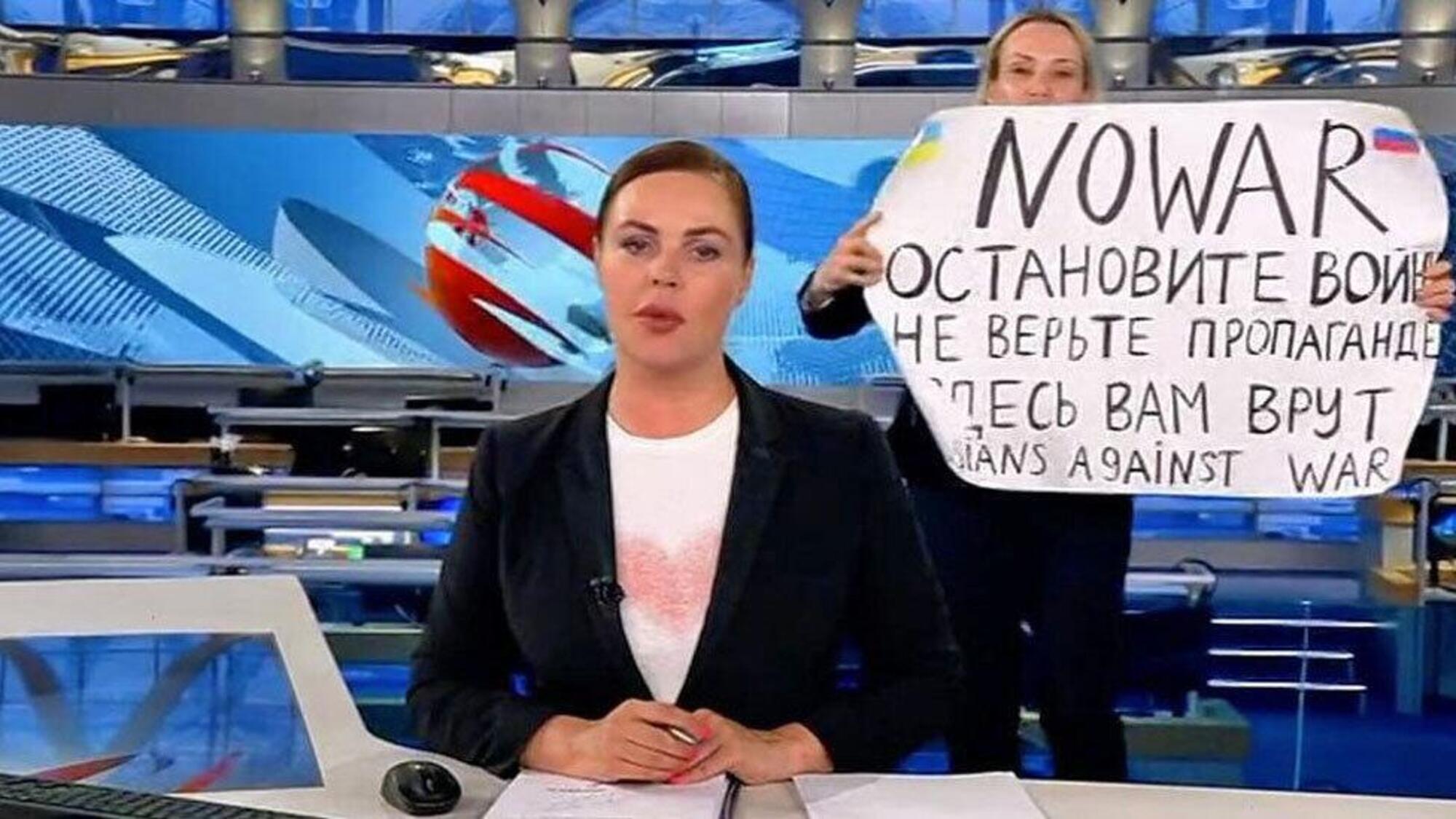 La giornalista Marina Ovsyannikova (sullo sfondo) diventa famosa per aver interrotto un tg russo con un cartello contro la guerra in Ucraina